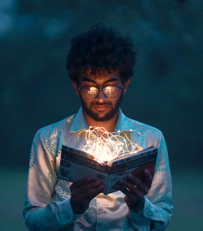 A man reading a book in the dark illuminated by soft light